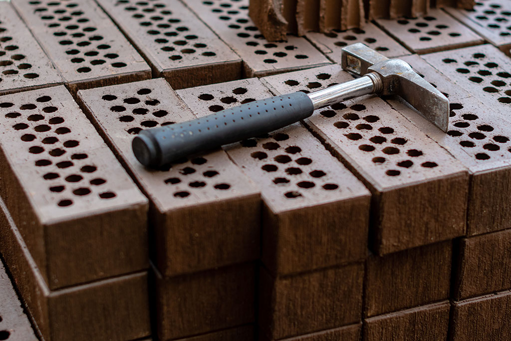 A hammer is laid on a red brick stack.